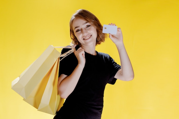 Mulher alegre com pacotes em fundo amarelo, viagem de compras. retrato de estúdio. venda de sexta-feira negra.