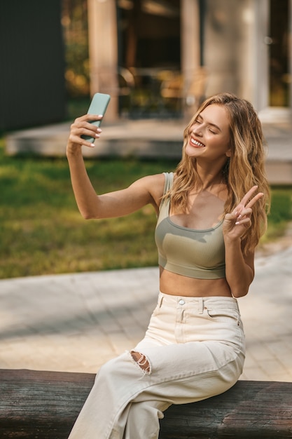 Mulher alegre com smartphone mostrando sinal de liberdade com os dedos