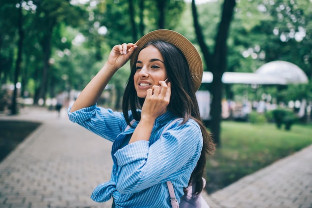 Mulher alegre com sorriso fofo se sentindo bem durante uma conversa amigável via telefone celular