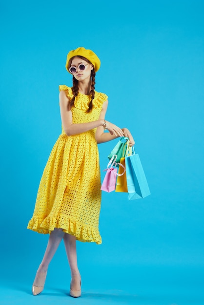 Mulher alegre com um chapéu amarelo shopaholic modelo de estúdio de estilo de moda