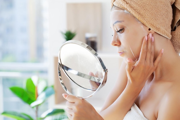 Mulher alegre com uma toalha na cabeça máscara facial pele limpa