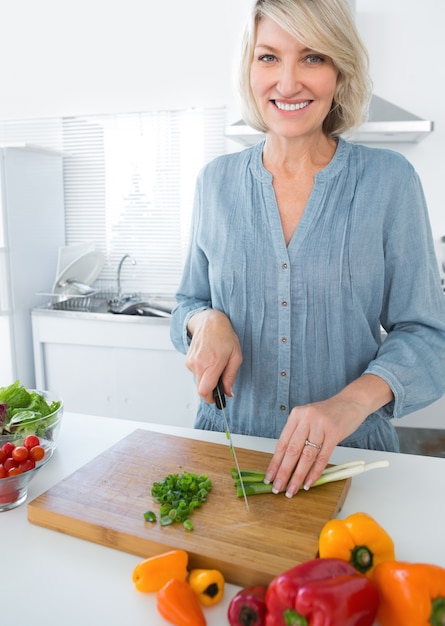 Mulher alegre cortando vegetais