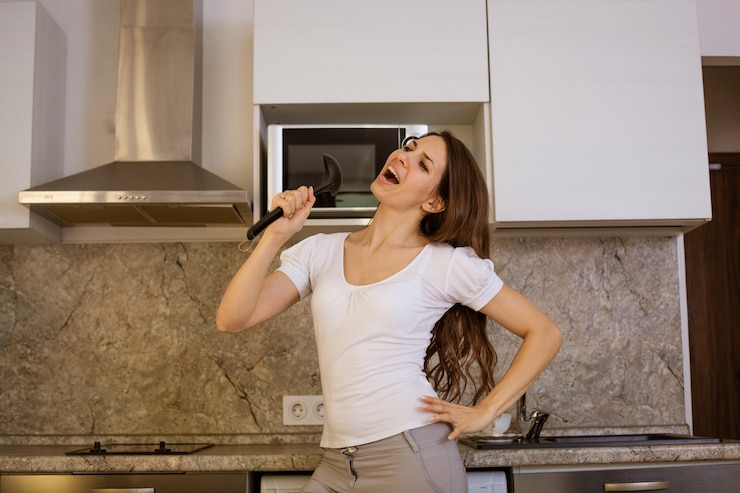 Foto mulher alegre e feliz cantando na cozinha com uma concha na mão