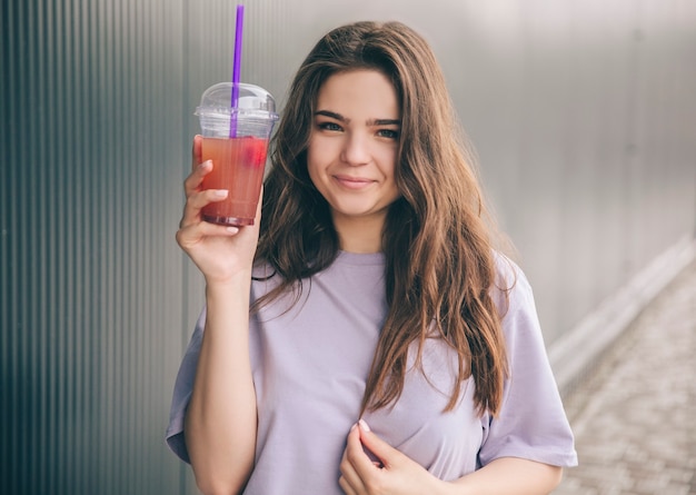 Foto mulher alegre e positiva posando com um copo de plástico na mão