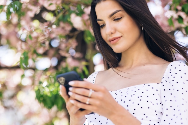 Mulher alegre olhando para o celular na rua urbana