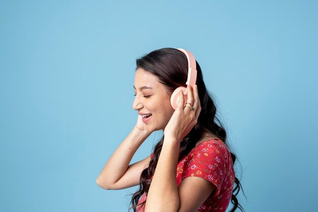 Mulher alegre ouvindo música com um fone de ouvido no fundo azul