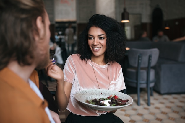 Mulher alegre sentada em um restaurante conversando com um amigo