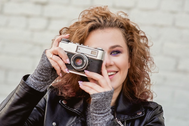 mulher alegre tirando fotos em uma câmera de filme antigo