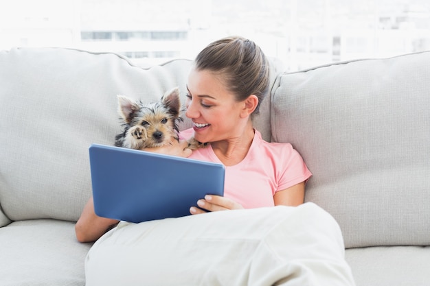 Mulher alegre usando tableta com seu yorkshire terrier