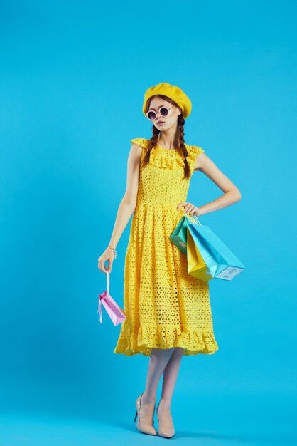 Mulher alegre vestido amarelo comprando diversão fundo azul