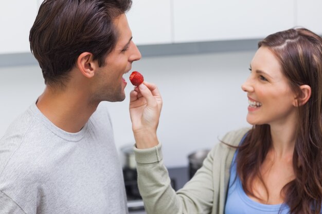 Mulher alimentando seu marido tomate cereja