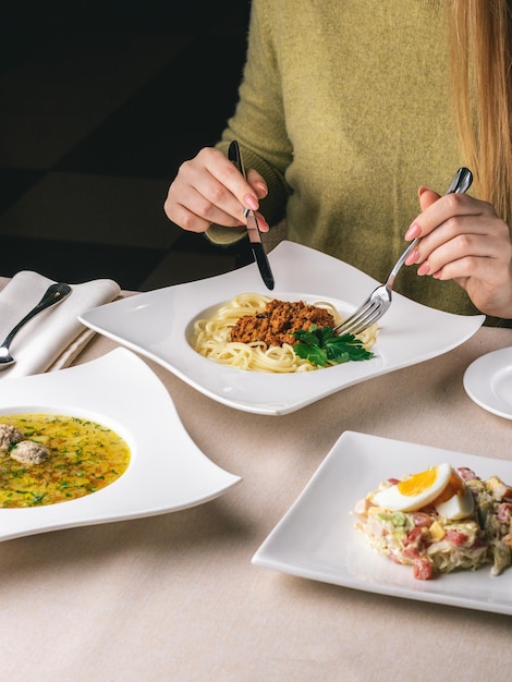 Mulher almoça no restaurante sopa branca e salada de macarrão e ovo