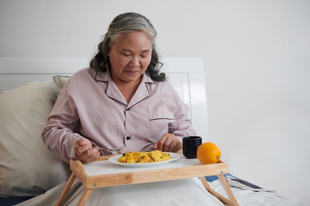 Mulher almoçando na cama