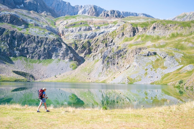 Mulher alpinista caminhando à beira do lago