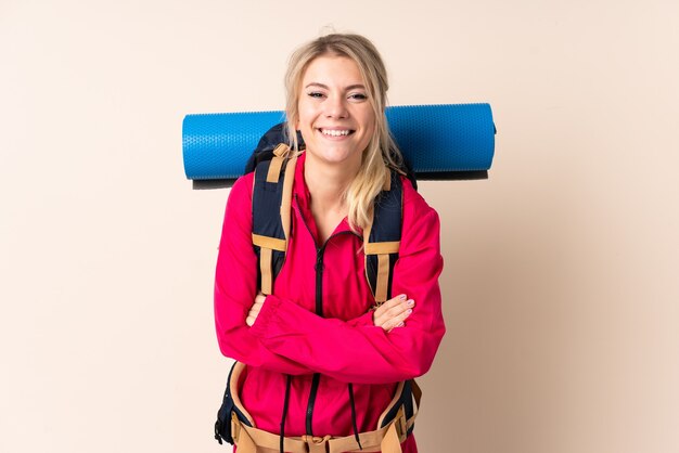 Mulher alpinista com uma grande mochila rindo sobre uma parede isolada