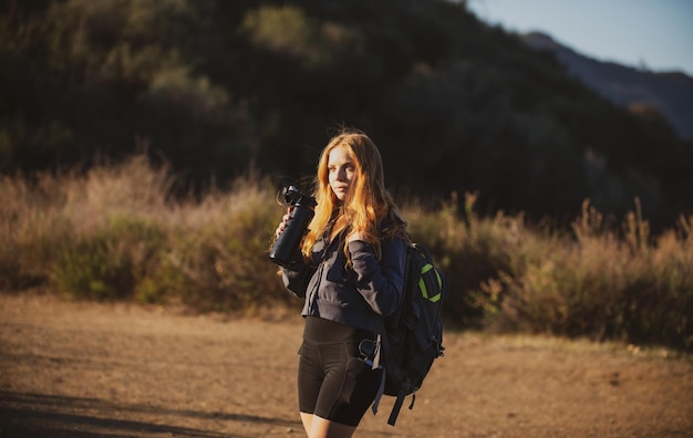 Mulher alpinista de conceito de turismo com mochila nas colinas turista caminhando nas montanhas com mochila