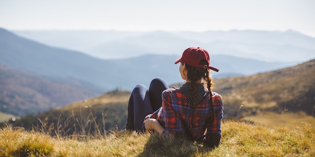 Mulher alpinista descansando, relaxando, sentada, aproveitando o sol durante uma caminhada, uma caminhada, uma bela jovem