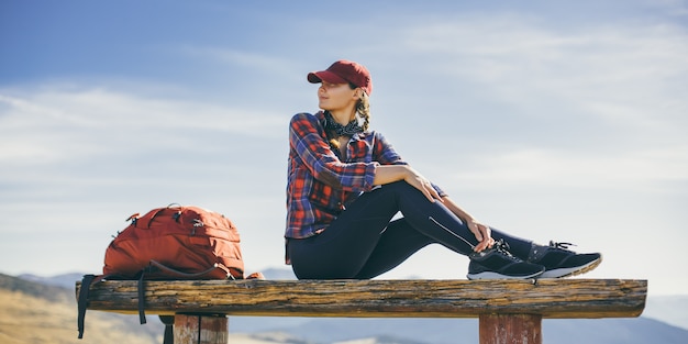 Mulher alpinista descansando sentada, aproveitando o sol durante a caminhada, caminhada, bela jovem mulher