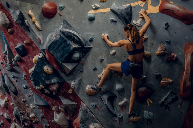 Mulher alpinista livre em boulder dentro de casa. vista traseira.