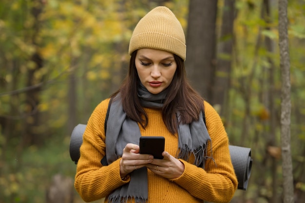 Mulher alpinista olha para o mapa no telefone e tenta encontrar caminho