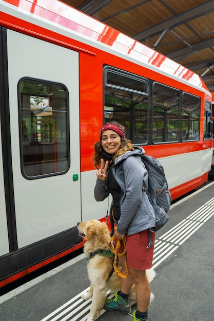 Mulher alpinista pegando o trem com seu cachorro