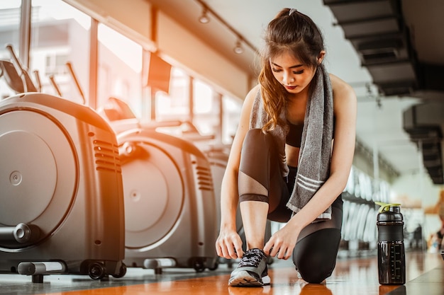 Mulher amarrando cadarços de sapatoFemale sport fitness se preparando para treino na academia