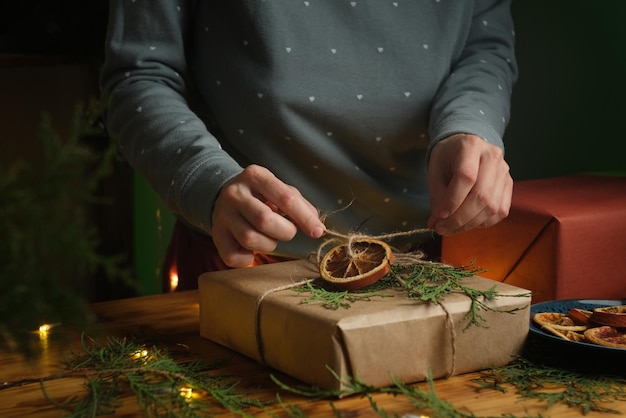 Mulher amarrar um laço na caixa com presente de Natal