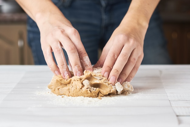 Mulher amassa a massa com as mãos na cozinha