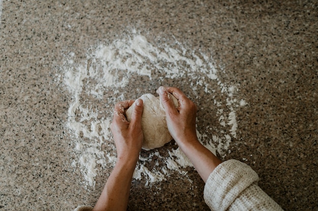 Mulher amassando massa fermentada na cozinha durante a quarentena