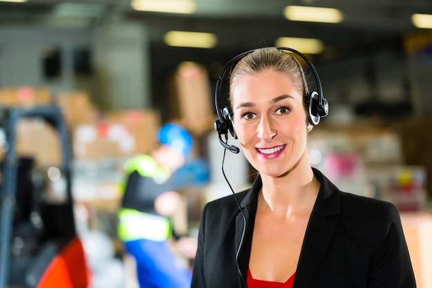 Mulher amigável, despachante ou supervisor usando fone de ouvido no armazém da empresa de encaminhamento,