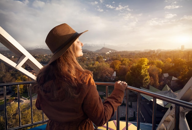 Mulher anda de roda gigante ao pôr do sol