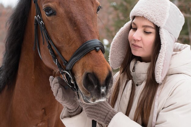 Mulher andando com cavalo em dia de inverno na floresta.