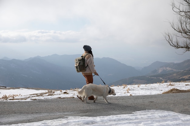 Foto mulher andando com seu labrador durante a viagem de inverno