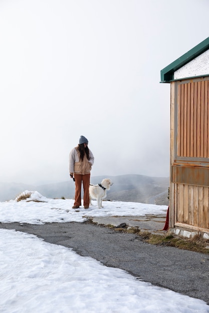 Foto mulher andando com seu labrador durante a viagem de inverno