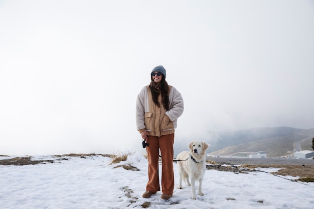 Foto mulher andando com seu labrador durante a viagem de inverno