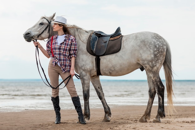 Mulher andando com um cavalo na praia