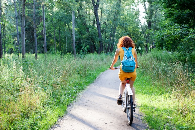 Mulher andando de bicicleta na floresta verde