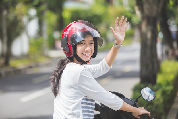 Mulher andando de moto e acenando a mão