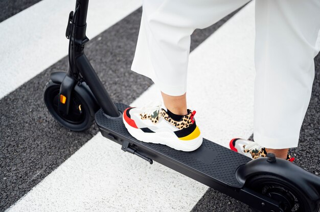 Mulher andando de scooter em uma passadeira no verão