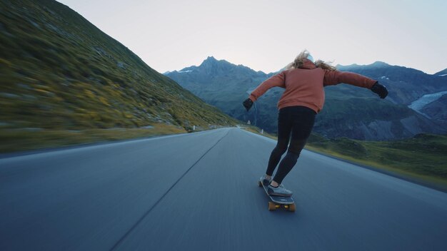 Mulher andando de skate e fazendo truques entre as curvas em uma passagem de montanha