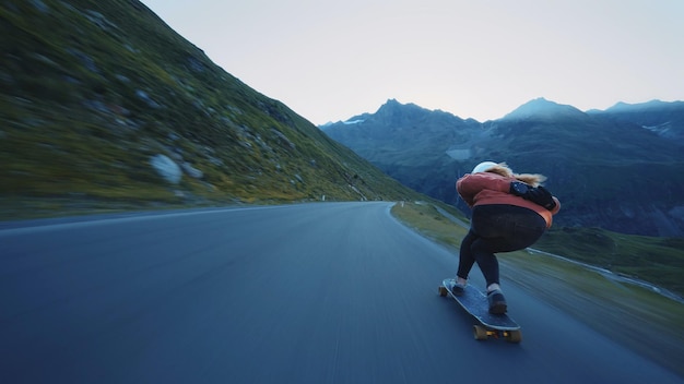 Mulher andando de skate e fazendo truques entre as curvas em uma passagem de montanha