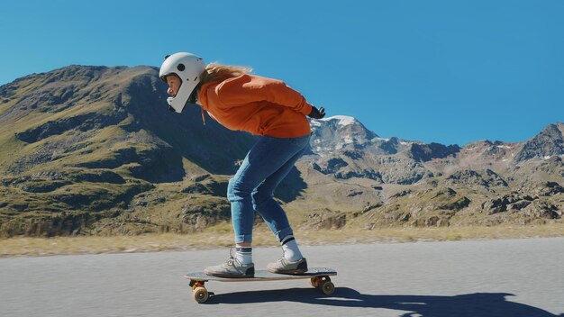 Mulher andando de skate e fazendo truques entre as curvas em uma passagem de montanha