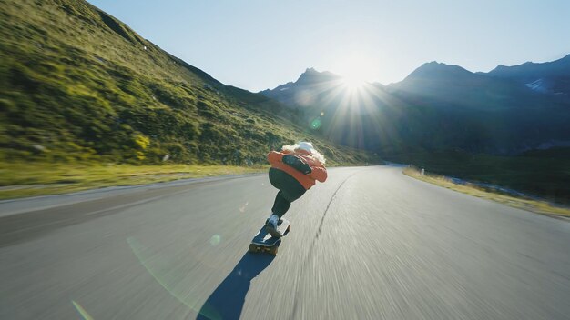 Foto mulher andando de skate e fazendo truques entre as curvas em uma passagem de montanha