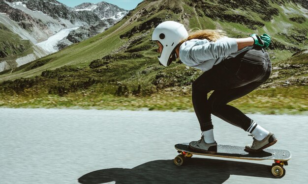 Mulher andando de skate e fazendo truques entre as curvas em uma passagem de montanha