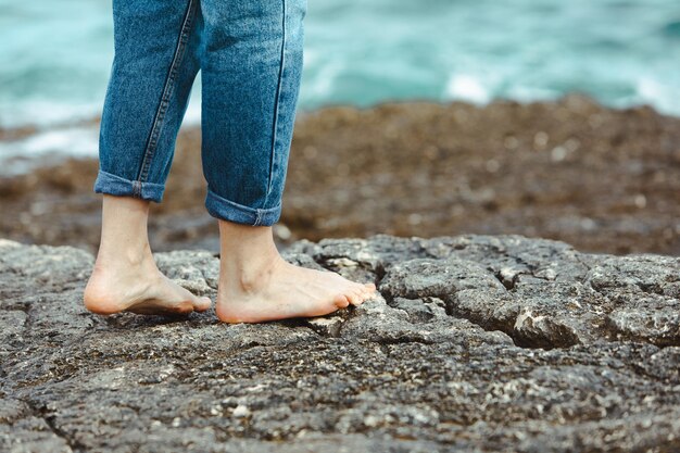 Mulher andando descalço à beira-mar de mãos dadas sapatos brancos férias de verão