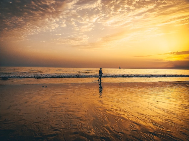 Mulher andando em uma praia em cádiz, pôr do sol.