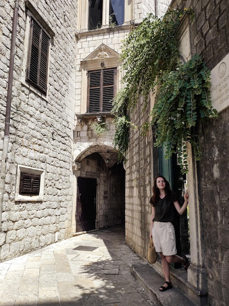 Mulher andando na pequena rua com edifícios de pedra na cidade velha Kotor Montenegro