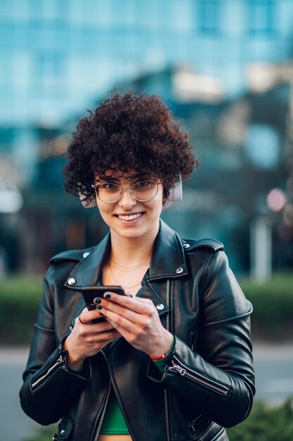 Mulher andando nas ruas da cidade e usando smartphone e fones de ouvido