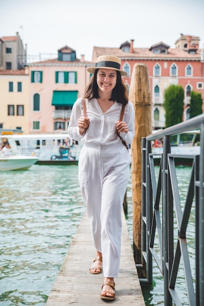 Mulher andando pelo cais de madeira olhando para o grande canal em veneza