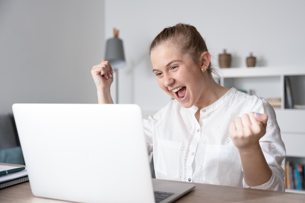 Mulher animada celebrando boas notícias na frente do laptop